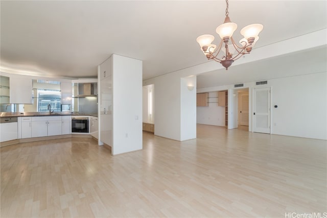 unfurnished living room featuring light hardwood / wood-style floors, a chandelier, and sink