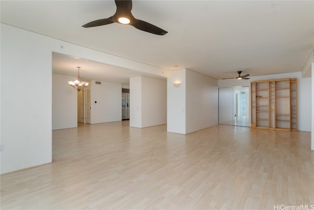 spare room featuring ceiling fan with notable chandelier and light wood-type flooring