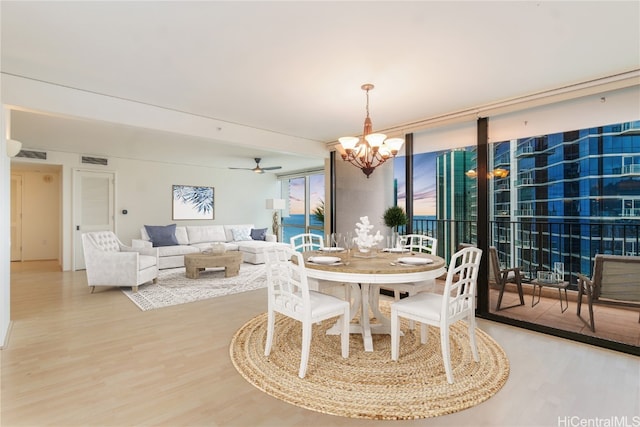 dining room with hardwood / wood-style floors and ceiling fan with notable chandelier