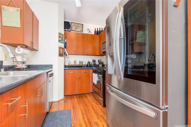 91-940 Puahala St Unit 39T, Ewa Beach, HI 96706 - kitchen featuring appliances with stainless steel finishes, a sink, a textured ceiling, brown cabinetry, and light wood-style flooring