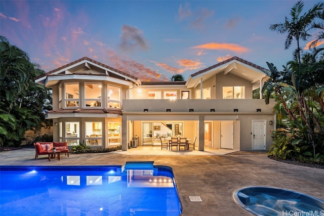 back house at dusk featuring a patio and a balcony