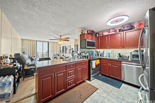 kitchen featuring kitchen peninsula, a textured ceiling, stainless steel appliances, ceiling fan, and light tile patterned flooring