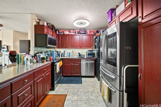 kitchen featuring backsplash, sink, light tile patterned floors, a textured ceiling, and stainless steel appliances