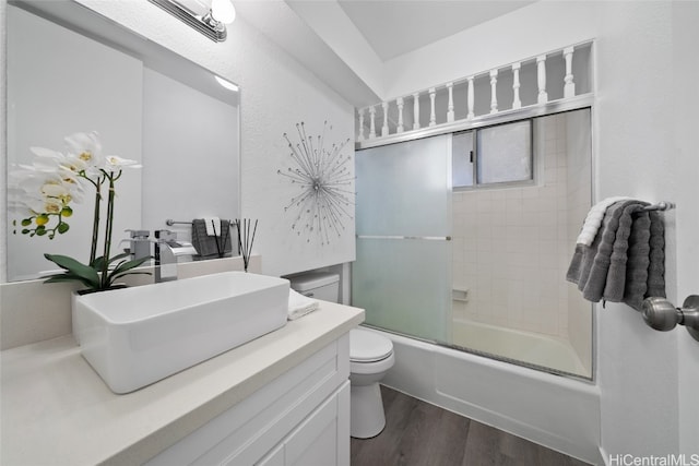 full bathroom featuring vanity, toilet, enclosed tub / shower combo, and hardwood / wood-style floors