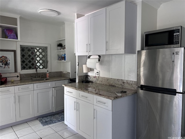 kitchen with light stone countertops, open shelves, white cabinets, a sink, and stainless steel appliances