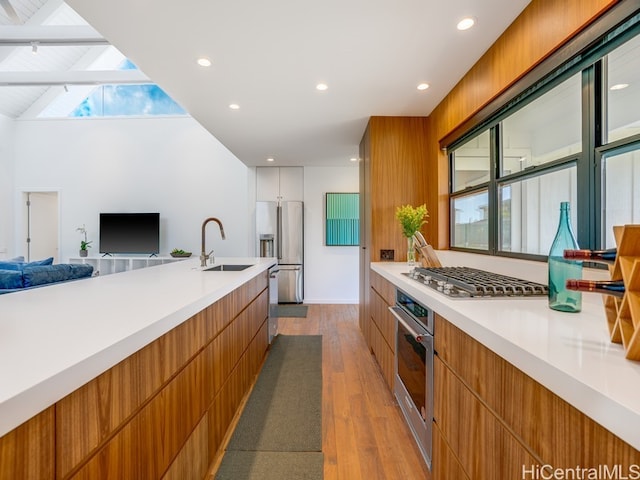 kitchen featuring lofted ceiling with beams, sink, appliances with stainless steel finishes, and light hardwood / wood-style floors