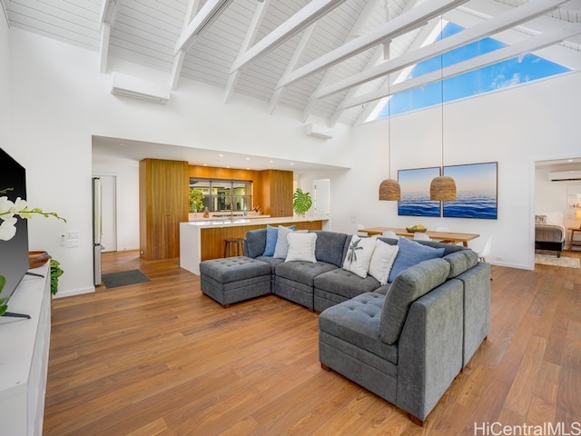 living room featuring a healthy amount of sunlight, light hardwood / wood-style flooring, a wall unit AC, and high vaulted ceiling