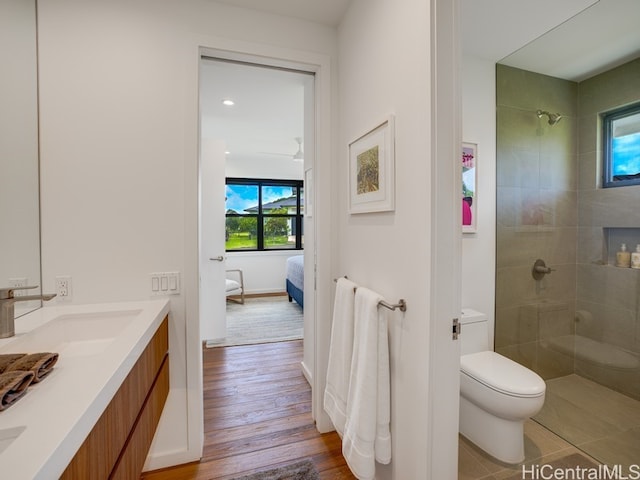 bathroom with vanity, toilet, wood-type flooring, and a tile shower