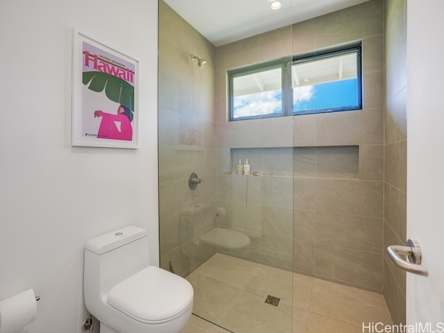 bathroom with a tile shower, toilet, and tile patterned flooring