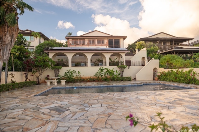 back house at dusk featuring a patio and a fenced in pool