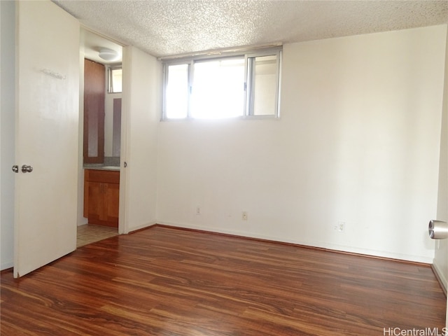 empty room with a textured ceiling and dark hardwood / wood-style flooring