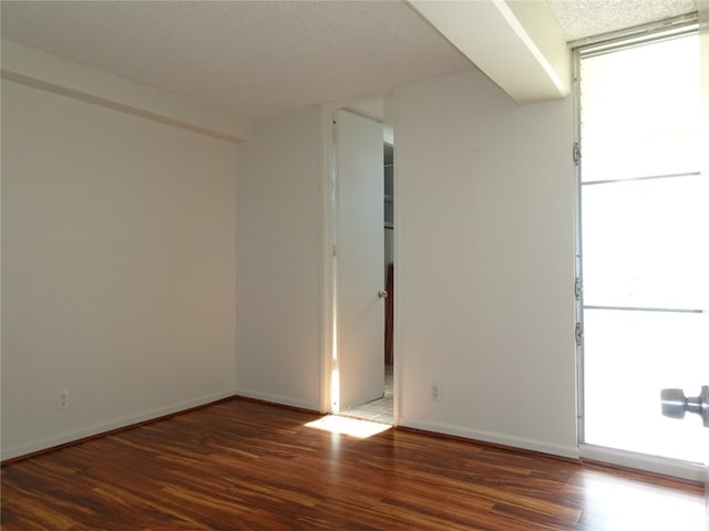 spare room with dark hardwood / wood-style floors and a textured ceiling