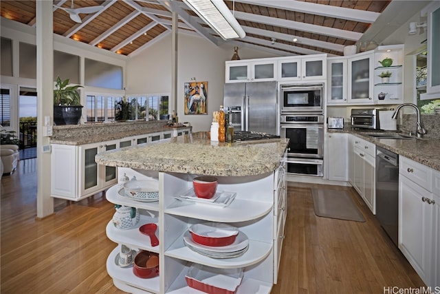 kitchen with sink, lofted ceiling with beams, built in appliances, a kitchen island, and wood ceiling