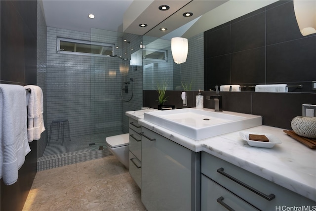 bathroom with a tile shower, vanity, and toilet