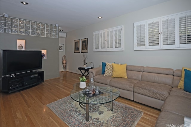 living room with wood-type flooring and an AC wall unit