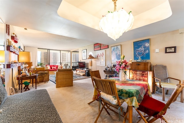 dining space with an inviting chandelier, a tray ceiling, and carpet flooring