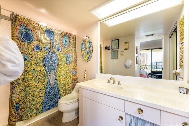 bathroom featuring toilet, a shower with curtain, wood-type flooring, vanity, and a skylight