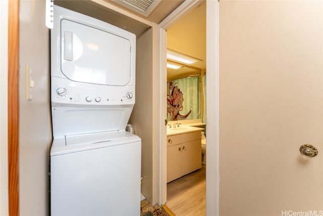 washroom with sink, stacked washer and clothes dryer, and light wood-type flooring