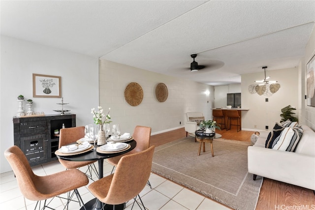 dining area with light hardwood / wood-style floors, a textured ceiling, and ceiling fan