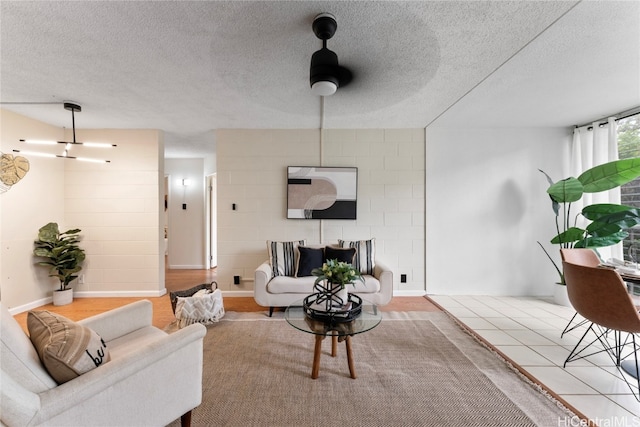 living room featuring ceiling fan, tile patterned flooring, and a textured ceiling