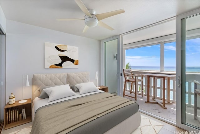 bedroom featuring a wall of windows, ceiling fan, access to exterior, a water view, and a beach view