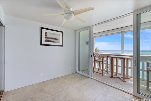 empty room featuring a view of the beach, ceiling fan, and a water view