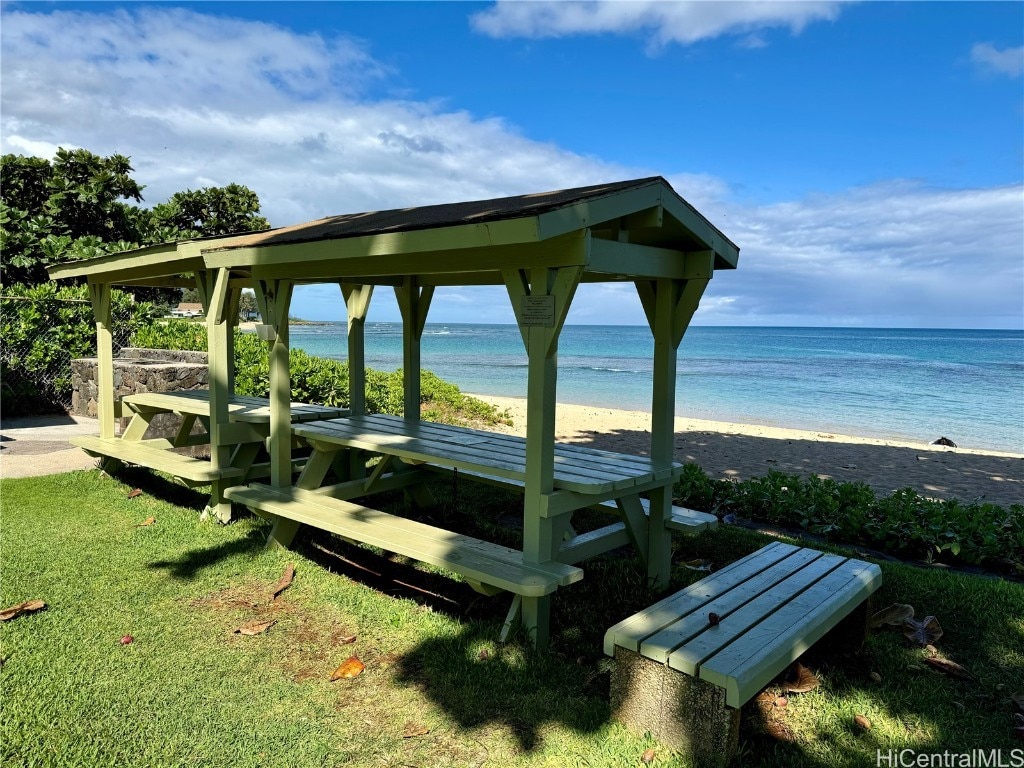 view of property's community with a gazebo, a view of the beach, a water view, and a yard