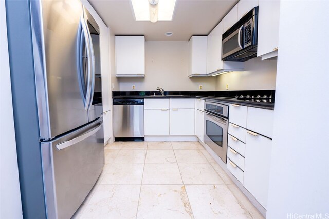 kitchen with white cabinetry, appliances with stainless steel finishes, a skylight, and sink