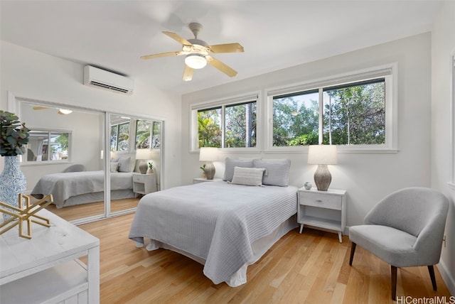 bedroom featuring a closet, a wall mounted AC, light hardwood / wood-style floors, and ceiling fan