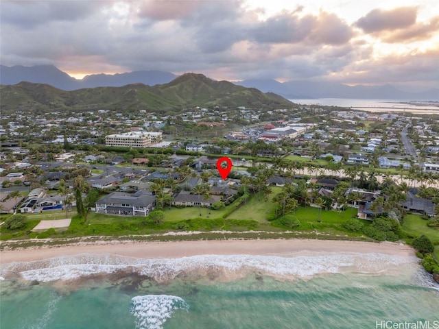 aerial view at dusk featuring a water and mountain view and a view of the beach