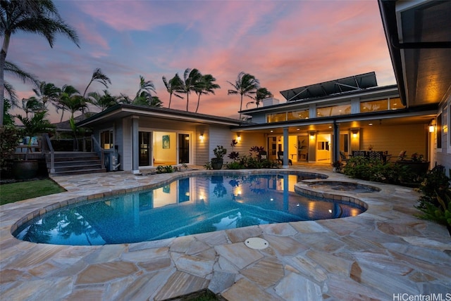 pool at dusk with an in ground hot tub and a patio area