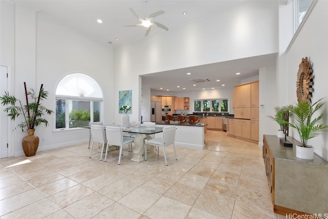 dining area featuring ceiling fan, crown molding, and a towering ceiling