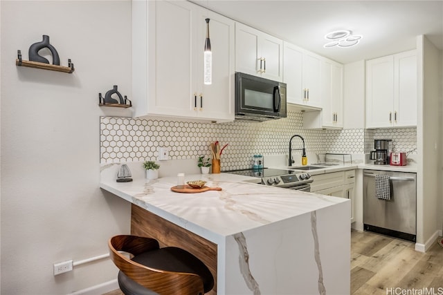 kitchen with backsplash, appliances with stainless steel finishes, kitchen peninsula, and white cabinets