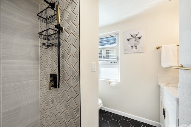 bathroom with vanity, tiled shower, and toilet