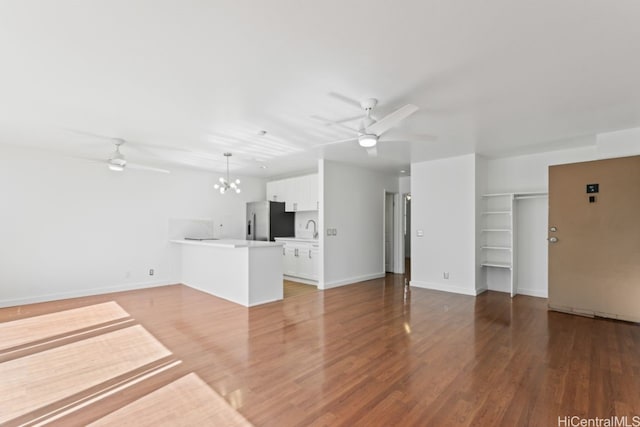 unfurnished living room with ceiling fan with notable chandelier, hardwood / wood-style flooring, and sink