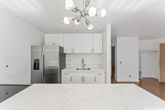 kitchen featuring sink, dark hardwood / wood-style floors, stainless steel fridge, decorative light fixtures, and white cabinetry