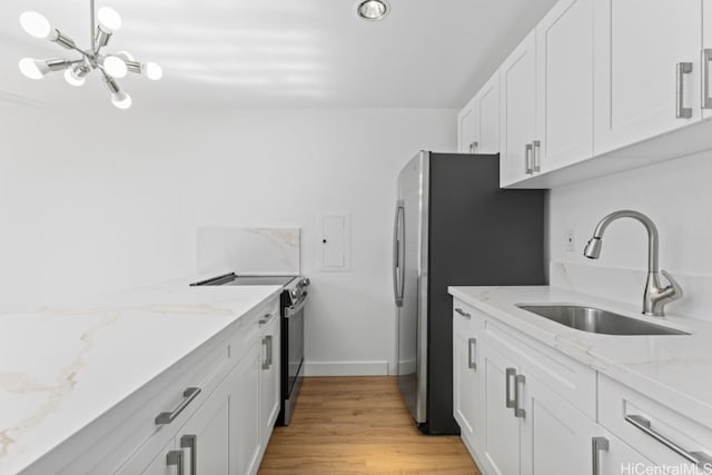 kitchen featuring sink, light stone counters, light hardwood / wood-style floors, white cabinets, and appliances with stainless steel finishes