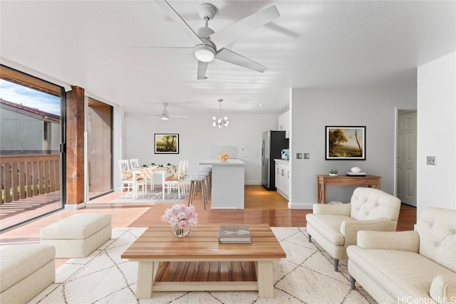 living room featuring light hardwood / wood-style floors and ceiling fan with notable chandelier