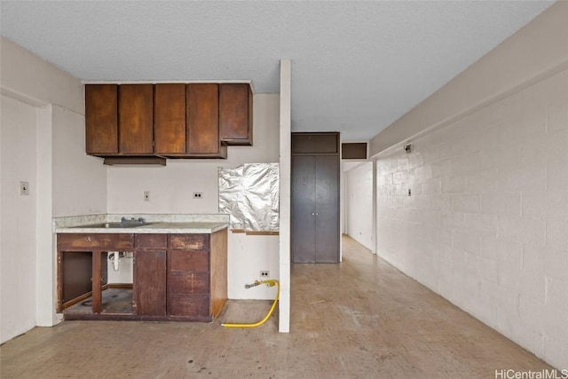 kitchen featuring a textured ceiling and dark brown cabinetry