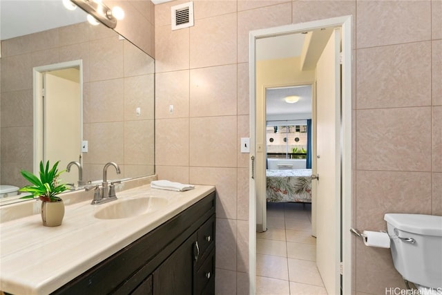 bathroom featuring vanity, tile walls, toilet, and tile patterned flooring