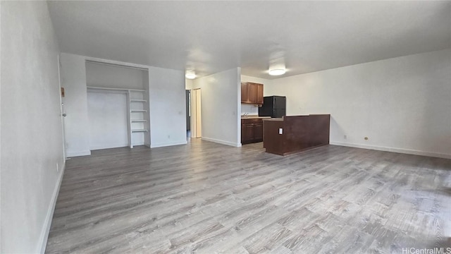 unfurnished living room featuring built in shelves and light wood-type flooring