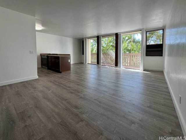 unfurnished living room featuring expansive windows, baseboards, and dark wood-style flooring