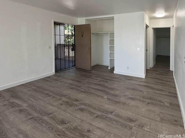 spare room featuring dark wood-type flooring and baseboards