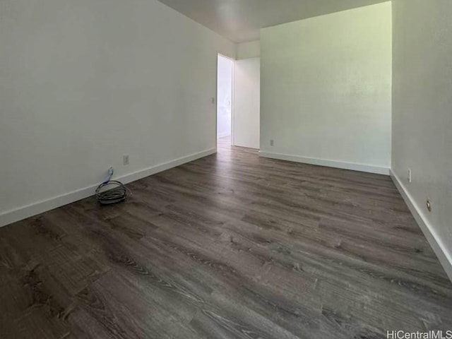 unfurnished room with baseboards and dark wood finished floors