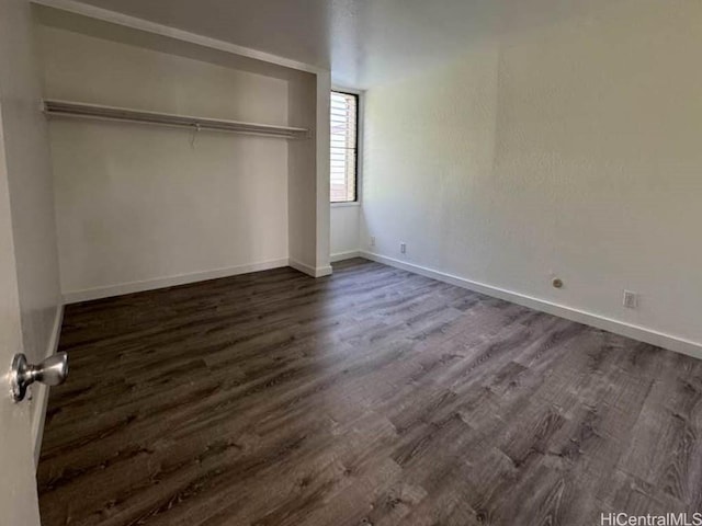 unfurnished bedroom with a closet, baseboards, and dark wood-style flooring