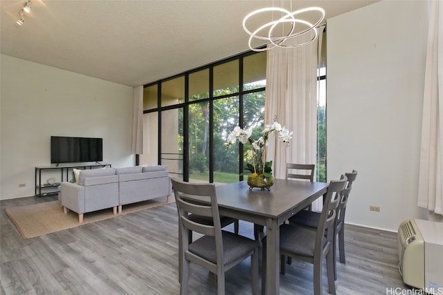 dining room featuring a chandelier, a textured ceiling, wood finished floors, and floor to ceiling windows