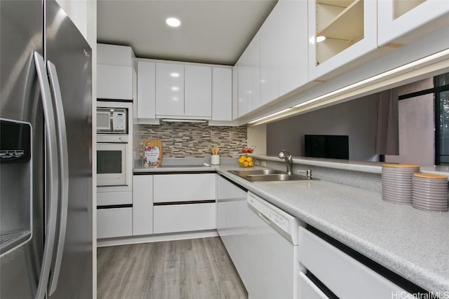 kitchen featuring white appliances, white cabinets, a sink, and modern cabinets