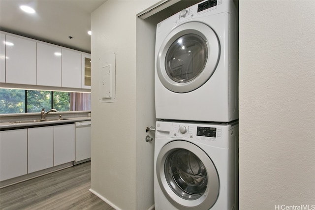 laundry room featuring light hardwood / wood-style floors, sink, and stacked washer / dryer