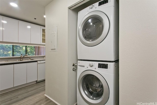 laundry area with stacked washer and dryer, laundry area, light wood-style floors, and a sink