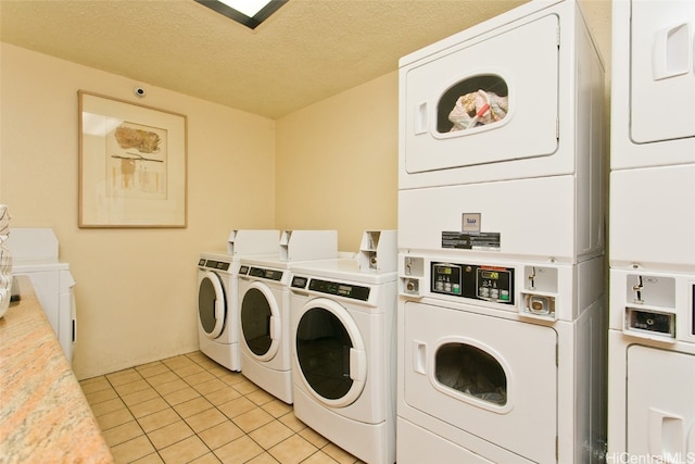 clothes washing area with stacked washer / drying machine, a textured ceiling, light tile patterned floors, and washing machine and clothes dryer